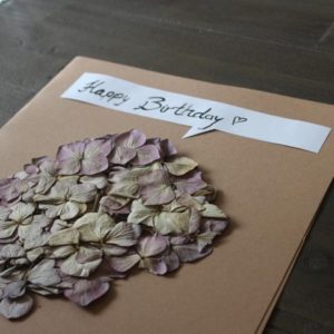 Geburtstagskarte aus Packpapier und einer getrockneten Blume Hand im Glück