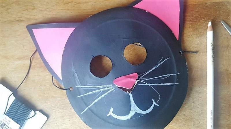 Maske aus Pappteller Katze mit einem weißen Stift Munf und Schnurhaar malen Hand im Glück